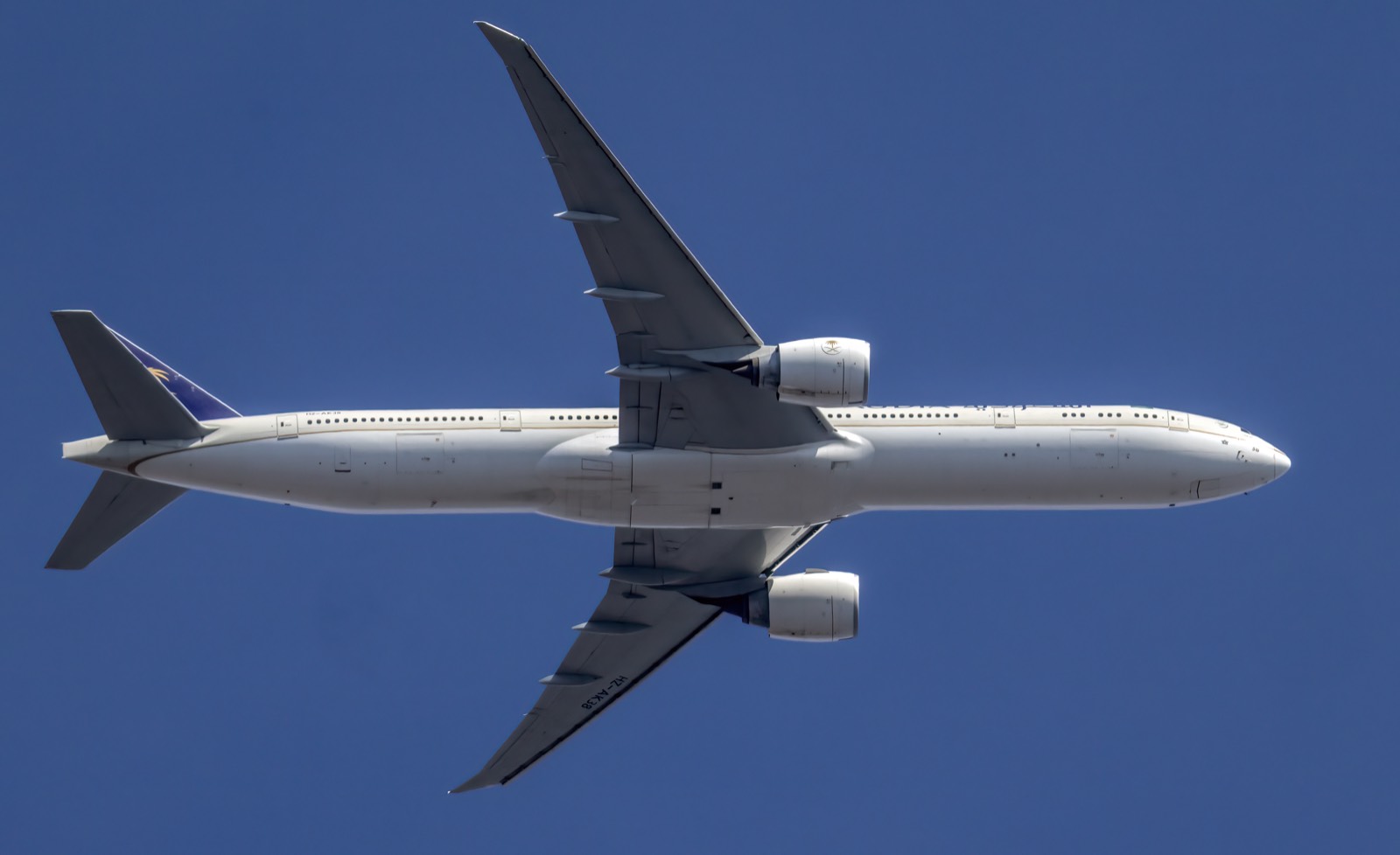 Saudia Boeing 777 in flight against a clear blue sky